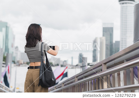 Solo southeast asian woman teenager blogger world travel explorer wait to take photo with smartphone. Local cultural experience and asia tourism concept express boat Chao Phraya River Bangkok Solo southeast asian woman teenager blogger world travel explorer wait to take photo with smartphone. Local cultural experience and asia tourism concept express boat Chao Phraya River Bangkok 128279229
