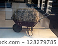A Rustic Wheelbarrow that is Overflowing with Freshly Gathered Hay from the Farm 128279785