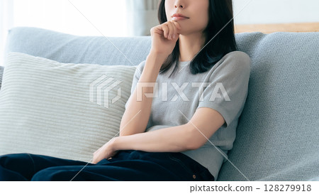 一位女士坐在沙發上思考 一位女士坐在沙發上思考 128279918