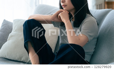 一位女士坐在沙發上思考 128279920