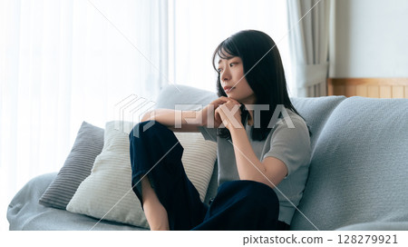 A woman sitting on a sofa and thinking A woman sitting on a sofa and thinking 128279921