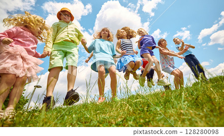 Children jumping in grassy field under summer sky Children jumping in grassy field under summer sky 128280098