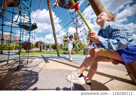 Children enjoying sunny day on playground climbing structures Children enjoying sunny day on playground climbing structures 128280111