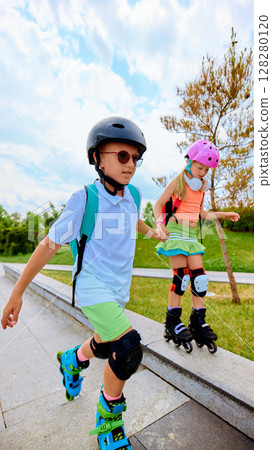Kids having fun rollerblading in a summer park Kids having fun rollerblading in a summer park 128280120