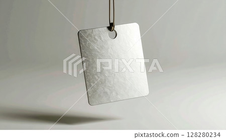 Minimalist blank square metallic tag with a small hole hanging from a st on a plain neutral background for labeling and identification purposes Minimalist blank square metallic tag with a small hole hanging from a st on a plain neutral background for labeling and identification purposes 128280234