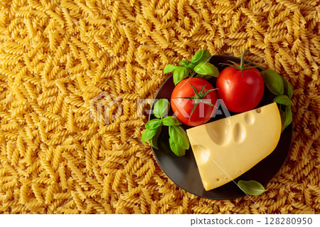 Uncooked fusilli pasta with tomatoes, basil and cheese. 128280950