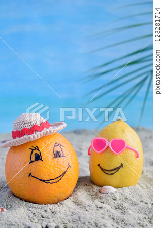 Creative minimal summer idea. Citrus hipster. Orange in bamboo hat and lemon in sunglasses on sand. Tropical beach concept. Creative art. Fun party Mood. Copy space 128281714