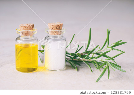 Rosemary essential oil in a small bottle and fresh twig on light background. Natural aroma cosmetic oil and salt 128281799