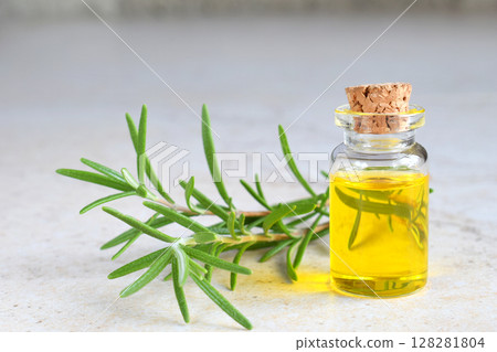 Rosemary essential oil in a small bottle and fresh twig on light background. Natural aroma cosmetic oil 128281804