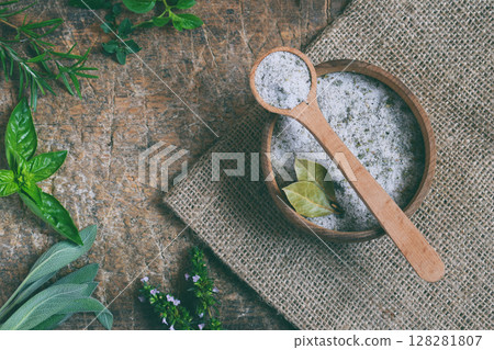 Ayurvedic herbal salt in wooden spoon. Sea salt with aromatic herb - rosemary, oregano, sage, marjoram, basil, thyme, mint, bay leaf. Copy space 128281807