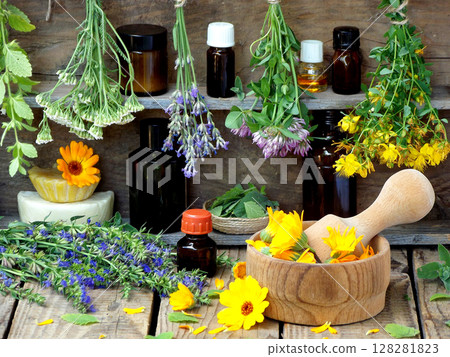 bunches of healing herbs - mint, yarrow, lavender, clover, hyssop, milfoil, mortar with flowers of calendula and bottles, herbal medicine 128281823