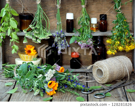 bunches of healing herbs - mint, yarrow, lavender, clover, hyssop, milfoil, mortar with flowers of calendula and bottles, herbal medicine 128281826