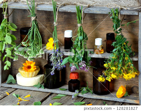bunches of healing herbs - mint, yarrow, lavender, clover, hyssop, milfoil, mortar with flowers of calendula and bottles, herbal medicine 128281827