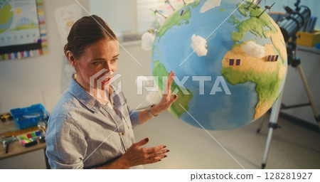 Female School Teacher Educating Science and Renewable Energy Sources Using Model of Planet Earth 128281927