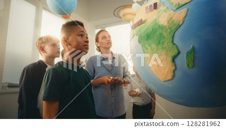 STEM Class: Female Teacher Explaining Renewable Energy to Team of Smart Kids Using Earth Model 128281962