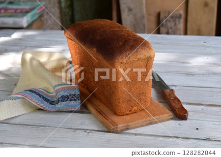 A loaf of white whole grain bread on a wooden background. Homemade Yeast Baking 128282044