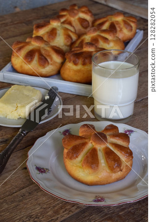 Buttermilk dinner buns in flower form served with butter, knife, glass of milk on wooden background. Fresh baked brioche. Homemade baking. Buttermilk dinner buns in flower form served with butter, knife, glass of milk on wooden background. Fresh baked brioche. Homemade baking. 128282054