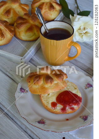 Buttermilk dinner buns in flower form served with butter, knife, glass of milk and jam on wooden background. Fresh baked brioche. Homemade baking 128282063