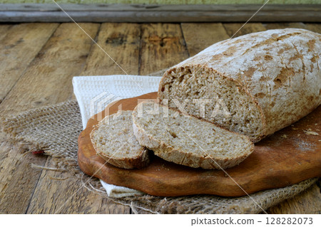 A loaf of homemade bread from whole grain  and rye flour whith sesame seeds on a wooden background. Copy space. Photographing with natural light 128282073