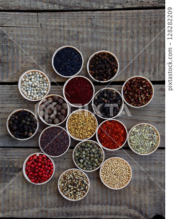 spices on a wooden background. Coriander, black pepper, paprika, mustard, turmeric, cumin, sumac, fenugreek, cloves, cubeb. 128282209