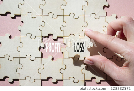 Profit or Loss symbol. Concept word Profit or Loss on wooden puzzle. Businessman hand. Beautiful pink background. Business and Profit or Loss concept. Copy space 128282571