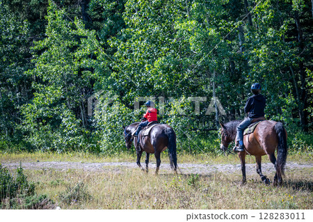 Line of tourists riding horses into the wilderness at Banff National Park, Canada Line of tourists riding horses into the wilderness at Banff National Park, Canada 128283011