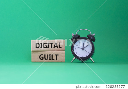 Digital Guilt symbol. Concept words Digital Guilt on wooden blocks. Beautiful green background with alarm clock. Business and Digital Guilt concept. Copy space. Digital Guilt symbol. Concept words Digital Guilt on wooden blocks. Beautiful green background with alarm clock. Business and Digital Guilt concept. Copy space. 128283277