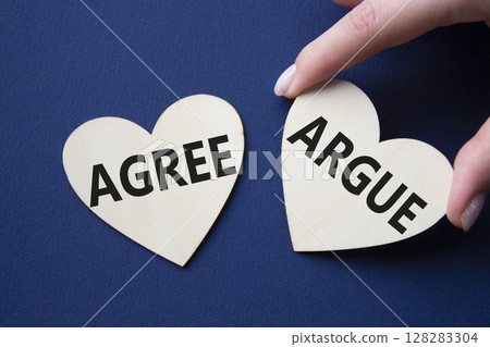 Agree or Argue symbol. Concept word Agree or Argue on wooden hearts. Businessman hand. Beautiful deep blue background. Business and Agree or Argue concept. Copy space Agree or Argue symbol. Concept word Agree or Argue on wooden hearts. Businessman hand. Beautiful deep blue background. Business and Agree or Argue concept. Copy space 128283304