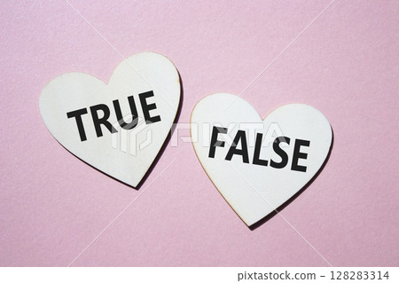 True or False symbol. Concept word True or False on wooden hearts. Beautiful pink background. Business and True or False concept. Copy space 128283314