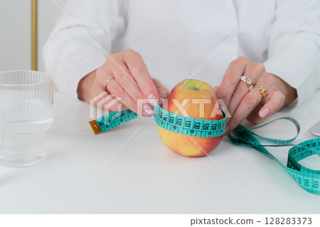A Healthy Lifestyle Advocate Displaying an Apple While Holding a Measuring Tape to Emphasize Nutrition and Health 128283373