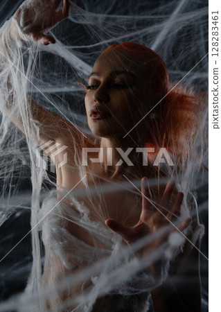 Woman entangled in a red net trap, showcasing ethereal beauty and mystery Woman entangled in a red net trap, showcasing ethereal beauty and mystery 128283461