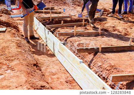 Workers are assembling wooden forms for foundation of new structure at construction site 128283848