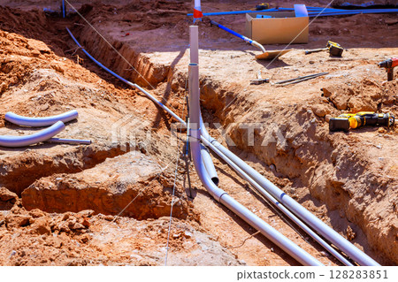 Workers install plumbing pipes in trench at construction site under works day 128283851