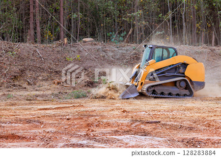 Excavator removes trees, clears land in rural setting, preparing area for upcoming construction activities. 128283884