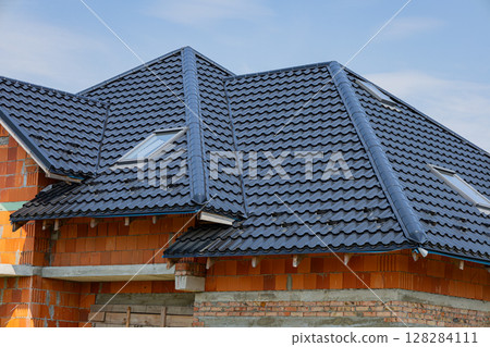 A recently completed metal roofing project highlights the durable tile design, enhancing the structure of a building under construction 128284111
