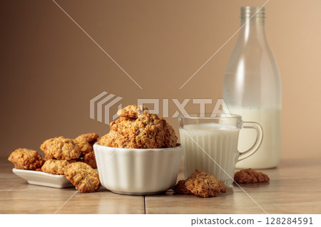 Oatmeal cookies and milk sit on a kitchen table. Oatmeal cookies and milk sit on a kitchen table. 128284591
