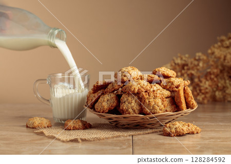 Oatmeal cookies and milk sit on a kitchen table. 128284592