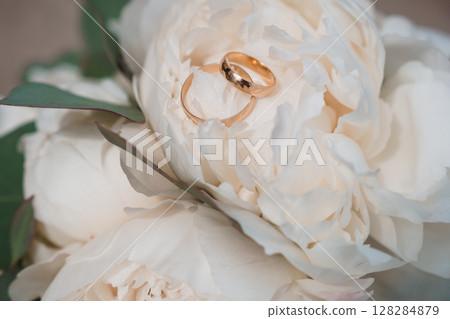 Elegant Wedding Rings on White Peony Bouquet, Close-Up, Gold Bands Symbolizing Love, Commitment, and Marriage Ceremony, Soft Focus Elegant Wedding Rings on White Peony Bouquet, Close-Up, Gold Bands Symbolizing Love, Commitment, and Marriage Ceremony, Soft Focus 128284879