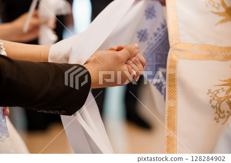 Hands Joined in Prayer at a Religious Ceremony: A Close-Up of Clasped Hands Under Robes with Gold Embroidery, Faith, Spirituality, Traditional Rituals. 128284902