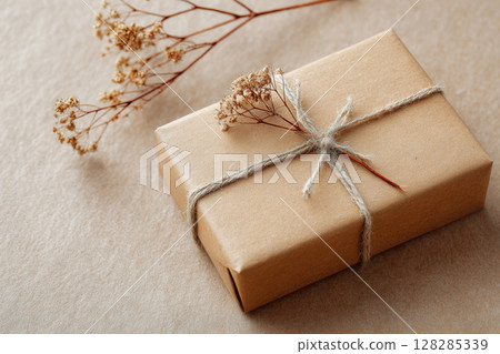 Gift box wrapped in plain kraft paper and tied with jute string 128285339