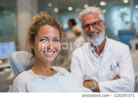 Woman sitting in dental chair with dentist standing nearby 128285371