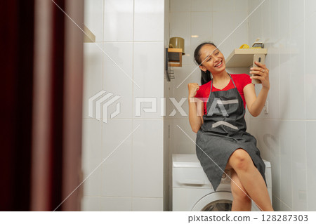 A woman is taking a selfie in her cozy and inviting laundry space area 128287303