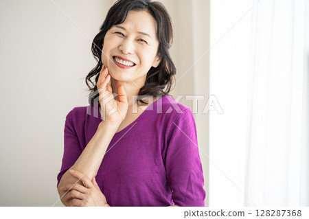 Portrait of a middle-aged woman in her 50s wearing a purple knit 128287368