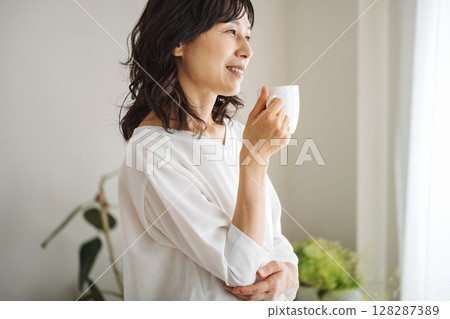 A middle-aged woman in her 50s drinking coffee at home A middle-aged woman in her 50s drinking coffee at home 128287389