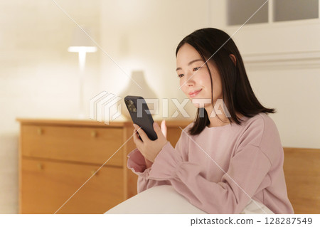 A woman looking at her smartphone in the middle of the night 128287549