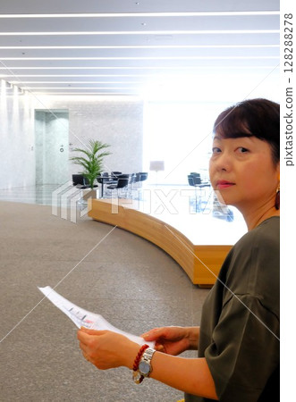 在自然光明亮的辦公室裡,一位女士拿著文件回頭看 在自然光明亮的辦公室裡,一位女士拿著文件回頭看 128288278