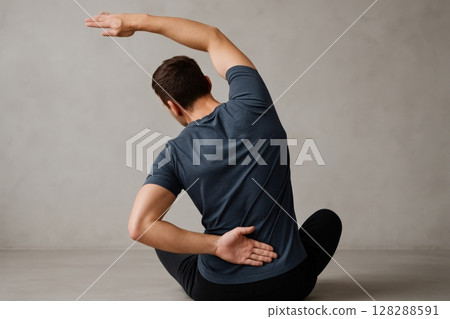 Man sitting and stretching back with one arm raised and other on lower back Man sitting and stretching back with one arm raised and other on lower back 128288591