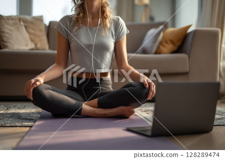 Young woman doing yoga stretches in the living room at home Young woman doing yoga stretches in the living room at home 128289474
