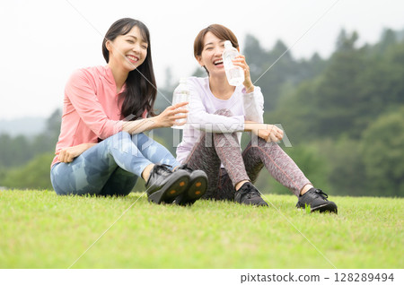 Two women rehydrating after exercise 128289494
