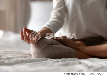 Close up of a woman hands in a lotus pose meditating on a bed at home 128289533